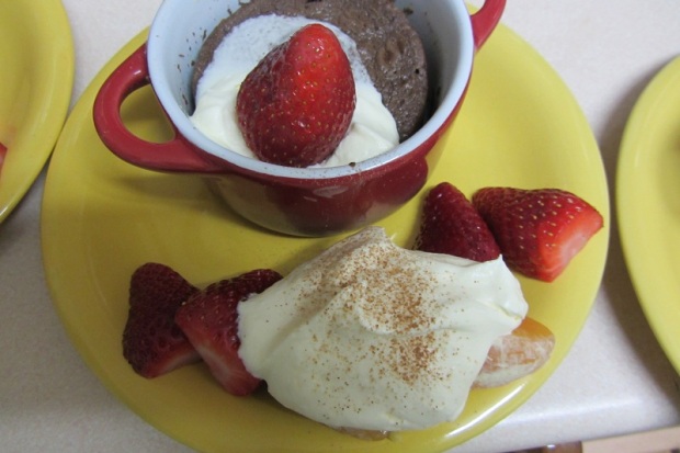 Warmer Schokoladenkuchen mit Erdbeeren und zerlaufener Schlagsahne.